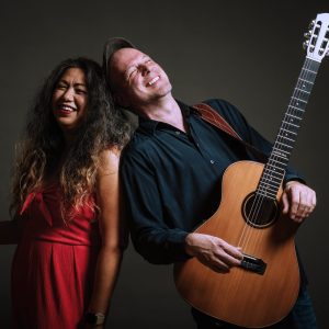 Auf dem Bild sind die Sängerin mit Fächer in der Hand und der Gitarrist mit Instrument des Duos 2enjoy zu sehen.