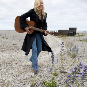 Auf dem Bild ist die schwedische Singer-Songwriterin Annika Fehling mit einer Gitarre in der Hand zu sehen.