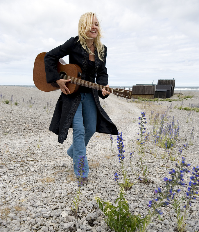 Auf dem Bild ist die schwedische Singer-Songwriterin Annika Fehling mit einer Gitarre in der Hand zu sehen.