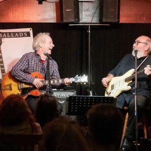 Auf dem Bild sind die beiden Musiker von Born 2B Blue auf der Bühne im Garniers Keller sitzend zu sehen.