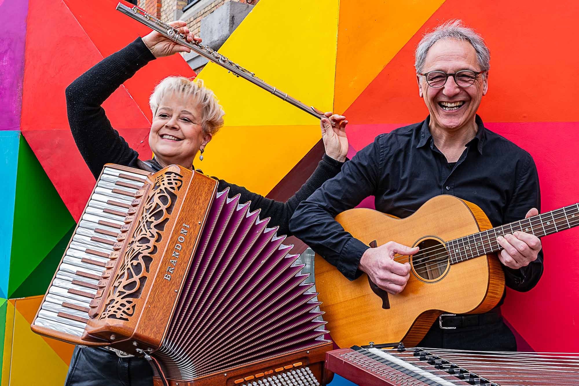 Auf dem Bild sind die beiden Musiker vom Duo Kaleido mit ihrem Instrumenten vor einer bunten Wand zu sehen.