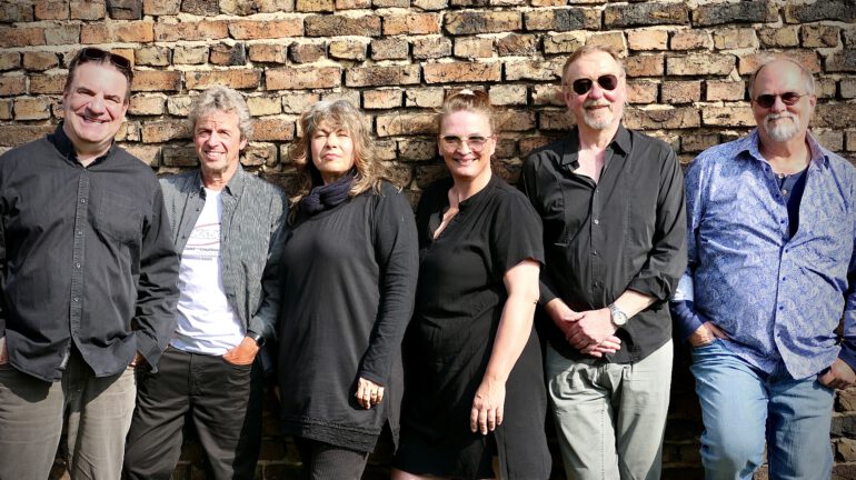 Auf dem Bild sind die sechs Musiker der Funkkapelle Rodheim vor einer Mauer stehend zu sehen.