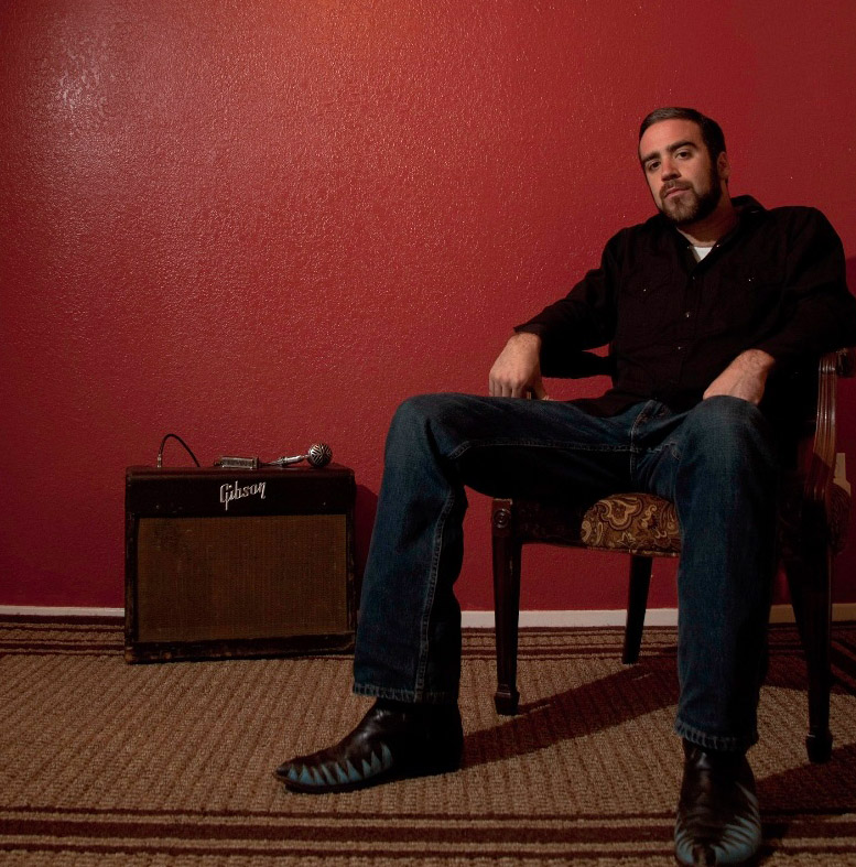 Auf dem Bild ist Greg Izor in einem Sessel sitzend zu sehen.