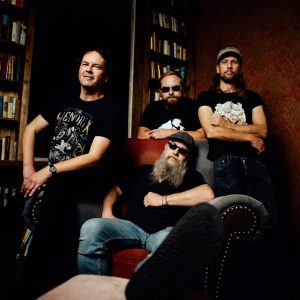 Auf dem Bild ist die vierköpfige Band Hot'n'Nasty vor einer Bücherwand stehend zu sehen.