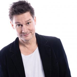 Auf dem Foto ist der Kabarettist Jens Neutag vor weißem Hintergrund zu sehen.