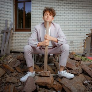 Auf dem Bild ist Matthias Ningel mit Vorschlaghammer auf einer Baustelle sitzend zu sehen.