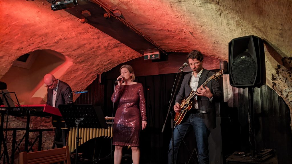 Auf dem Bild sind die drei Musiker von Trois à la fois auf der Bühne in Garniers Keller zu sehen.