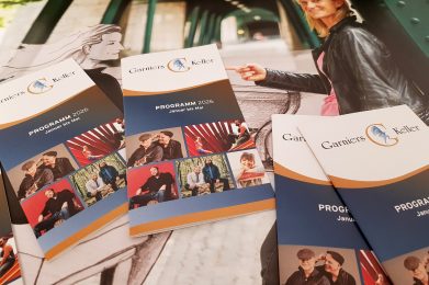 Auf dem Bild sind aktuelle Programmhefte vom Garnies Keller auf einem Plakat liegend zu sehen.