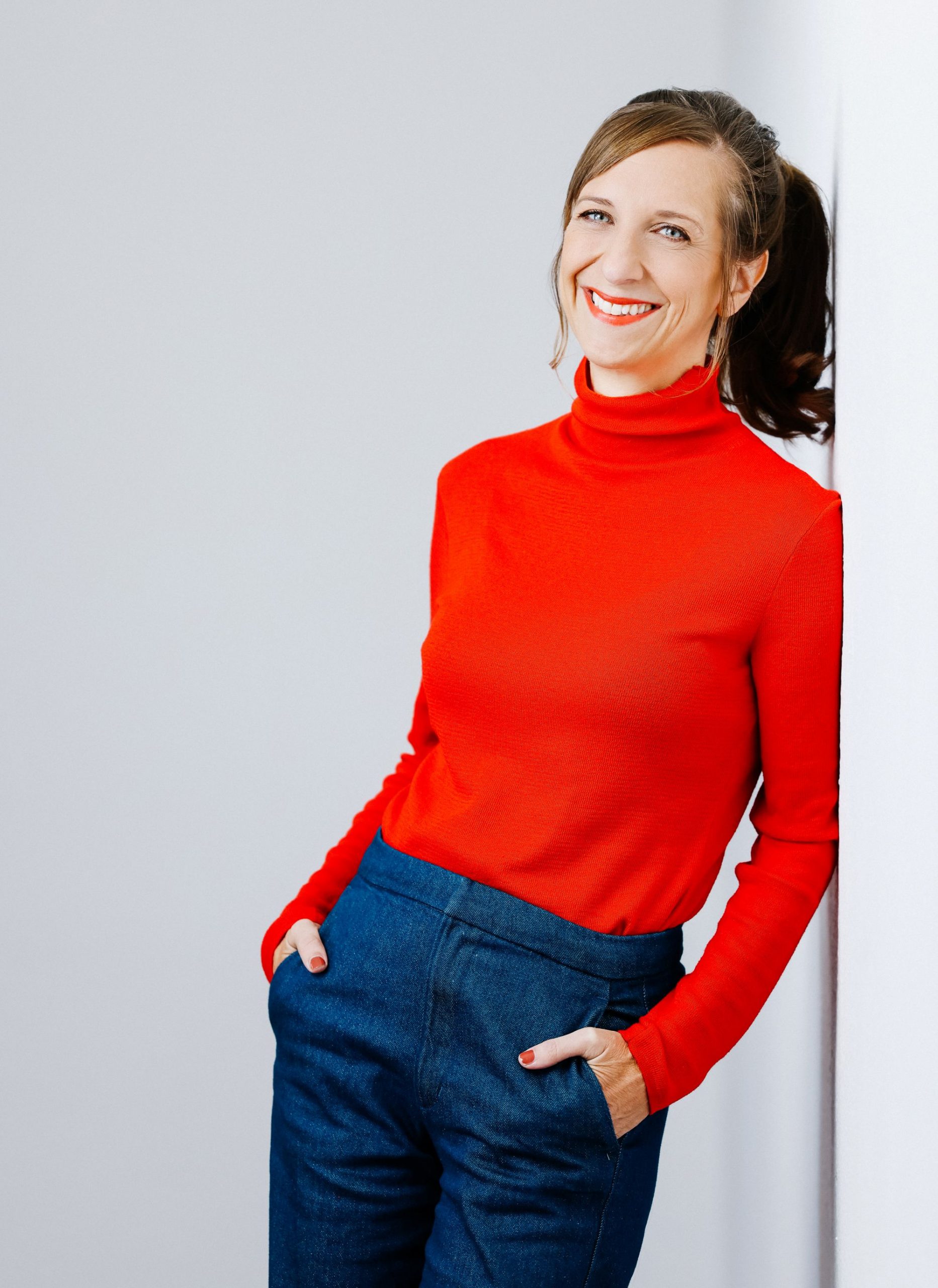 Auf dem Bild ist Sarah Hakenberg in einem roten Rollkragenpullover zu sehen.