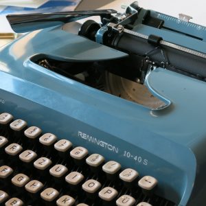 Auf dem Bild ist eine alte Remington Schreibmaschine in Blau zu sehen.