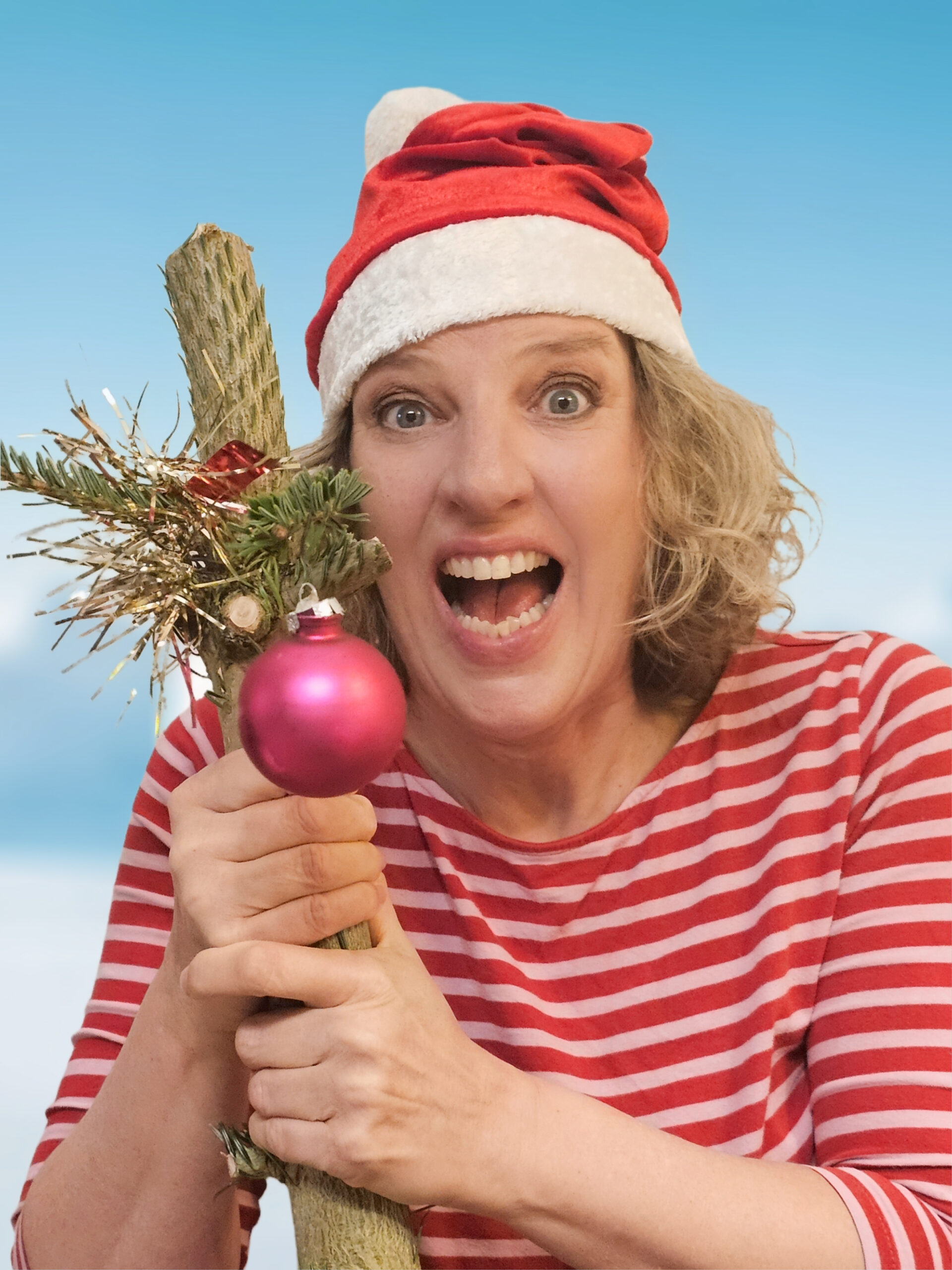 Auf dem Bild ist Sia Korthaus mit Weihnachtsmannmütze und dem Stamm eines Weihnachtsbaums, an dem noch eine Kugel hängt, zu sehen.