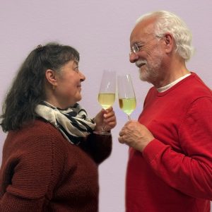 Auf dem Bild sind ein Mann und eine Frau zu sehen, die sich zuprosten.