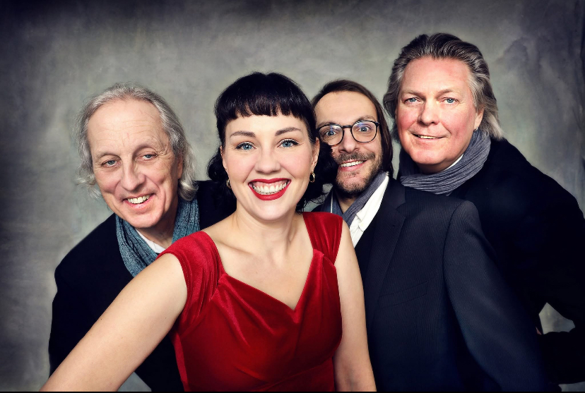 Auf dem Bild ist Sängerin Anja Tschenisch in rotem Kleid mit ihren drei Musikerkollegen von Woman in Boogie & Blues zu sehen.